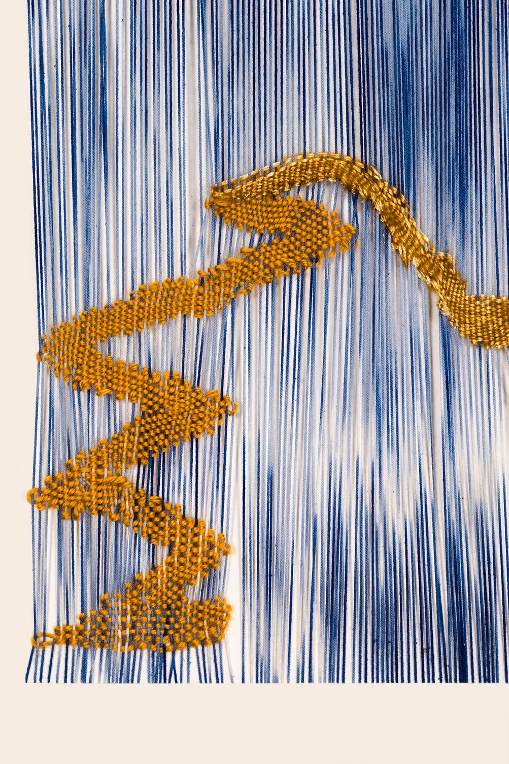 Detail of It is a Journey: an ochre woven line zigzagging down over loose blue and white ikat-dyed warp threads