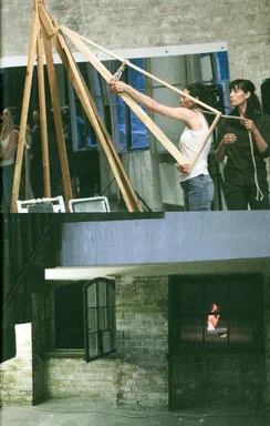 Unacknowledged Loss, page 115: two stacked photographs; top, a dancer raises a wooden frame tied with rope; bottom, a brick set with window frames, one framing a seated figure in the distance