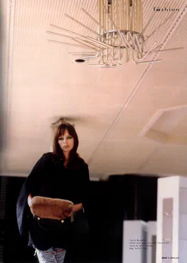 ahead, Winter 2004/05, page 25: color photograph closing the fashion section, a woman in a black open-sleeve jacket by Claudia Hill standing beneath a spiky ceiling light fixture